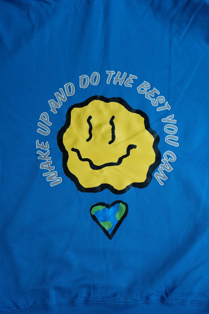 Image of wiggly circular yellow smiley face, with a heart underneath with blue and green design. Around the image, it says "Wake up and do the best you can"
